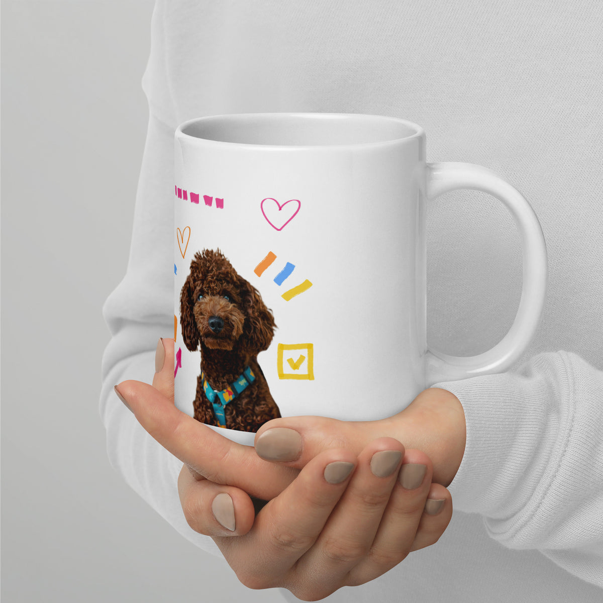 This custom white ceramic mug features an adorable brown poodle portrait surrounded by playful hand-drawn doodles, including hearts, checkmarks and colourful marker strokes.
Vibrant, whimsical decorations wrap around both sides of the cup, making it a sweet personalized gift for dog lovers.
Perfect for enjoying your morning coffee while showing off your love for your furry friend.